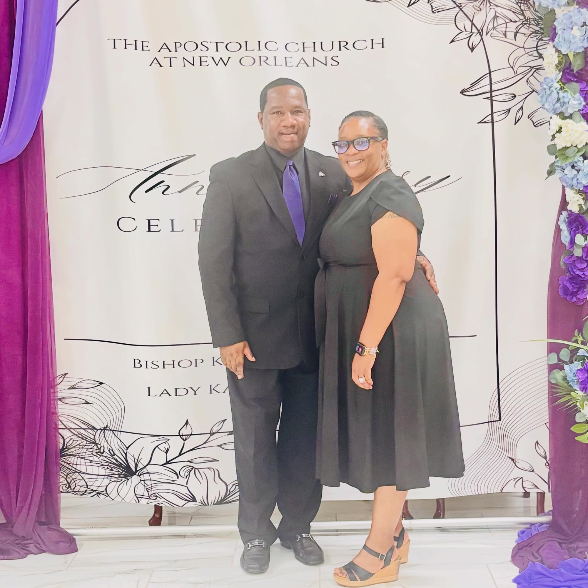 Pastor Charlie Grear Jr. and Lady Terri Grear in black in front of an anniversary backdrop at Church at New Orleans